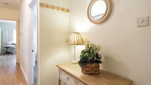 A room with a wooden desk, a lamp, a mirror, and a basket with flowers. - 2 bed Bungalow in Towcester by ARP Homes, 15 min from Silverstone, Free Parking, Perfect for Families and Contractors (West Northamptonshire)