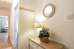 A room with a wooden desk, a lamp, a mirror, and a basket with flowers. - 2 bed Bungalow in Towcester by ARP Homes, 15 min from Silverstone, Free Parking, Perfect for Families and Contractors (West Northamptonshire)
