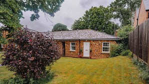 A brick house with a tiled roof, a front door, and a small front yard. - 2 bed Bungalow in Towcester by ARP Homes, 15 min from Silverstone, Free Parking, Perfect for Families and Contractors (West Northamptonshire)