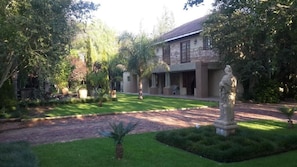 Une maison avec un jardin, une statue et une allée pavée.