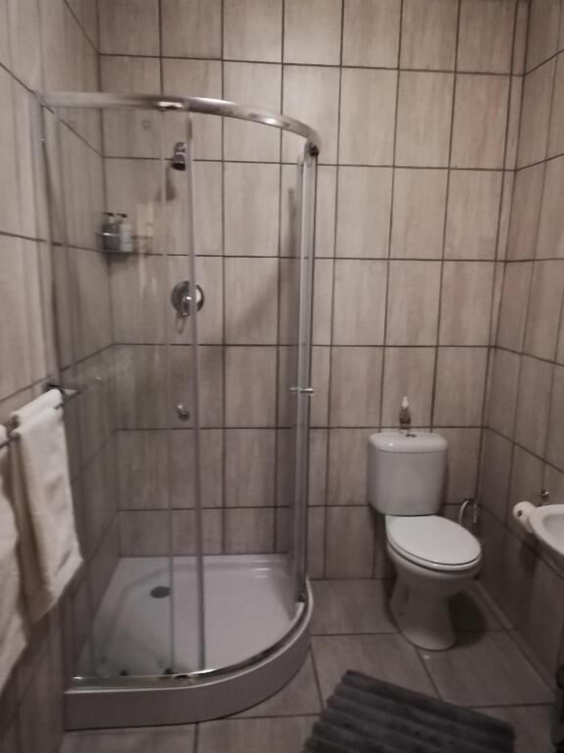 A shower with a glass door, a toilet, and a sink in a tiled bathroom.