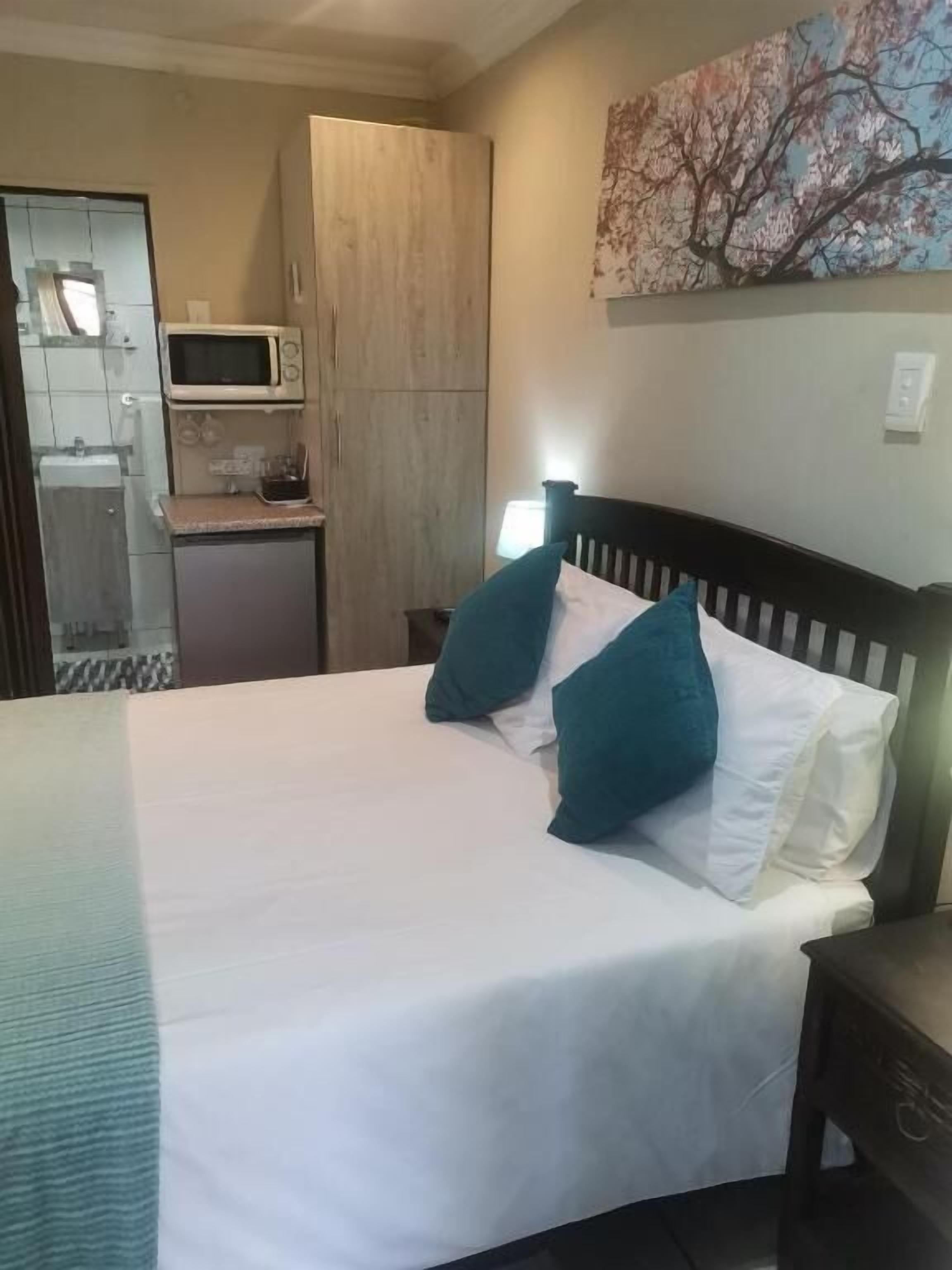 Une chambre à coucher comprenant un lit, des oreillers, une table de chevet, un four à micro-ondes et un placard.