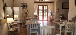 Un espace repas avec des meubles en bois, un lustre et une vue à travers une porte vitrée.