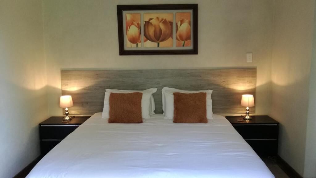 Une chambre d’hôtel avec un grand lit, deux tables de chevet et un tableau accroché au mur.