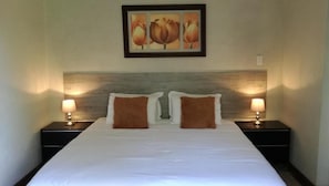 Une chambre d’hôtel avec un grand lit, deux tables de chevet et un tableau accroché au mur.