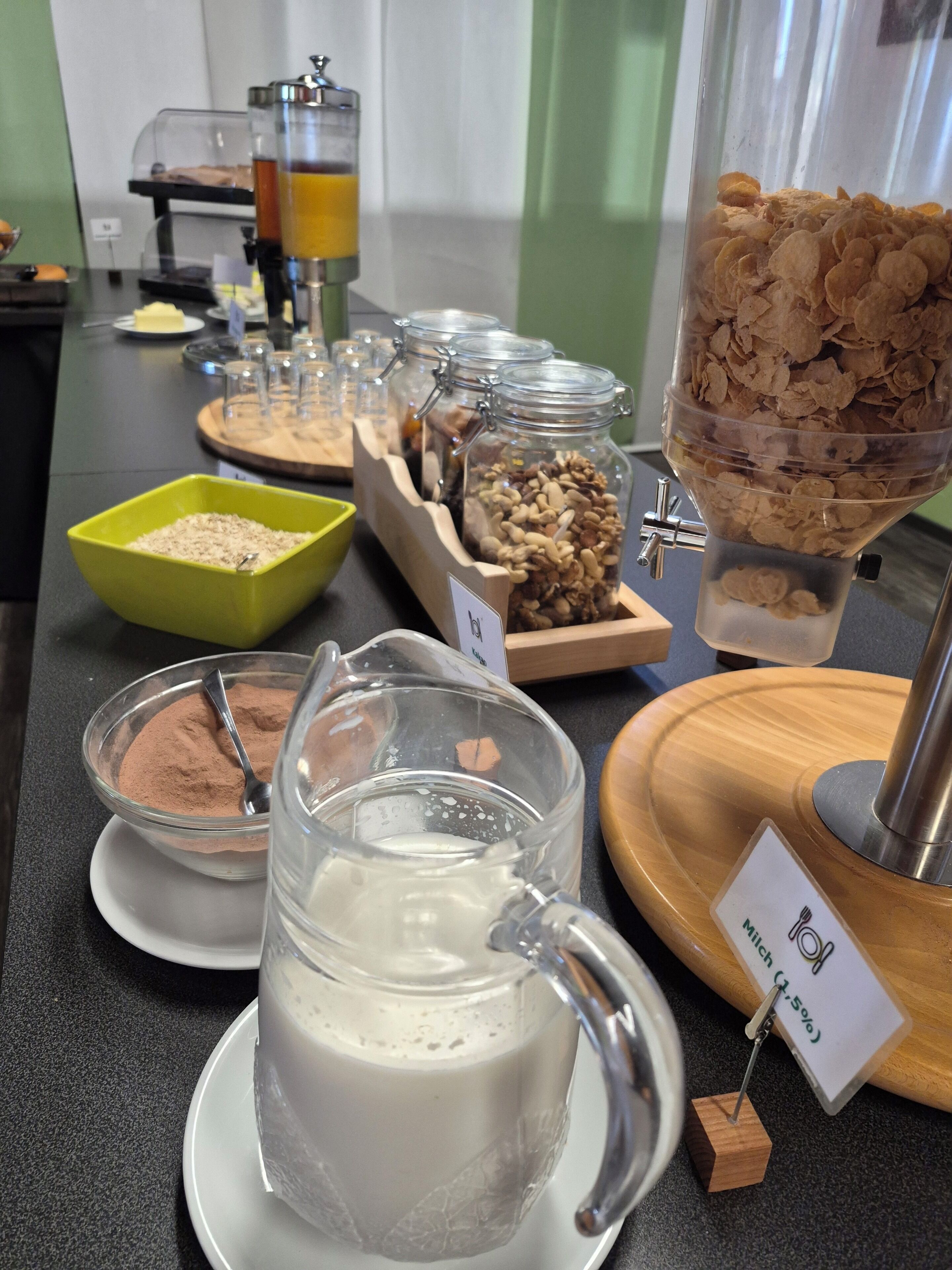 Ein Buffet mit verschiedenen Speisen, einer Milchkaraffe und einer Kaffeemaschine.