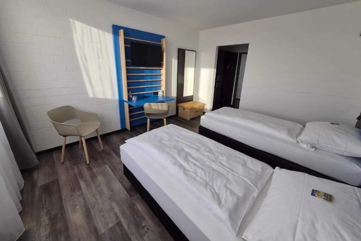 A room with two beds, a desk, a chair, and a wardrobe.
