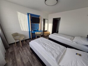 A room with two beds, a desk, a chair, and a wardrobe.