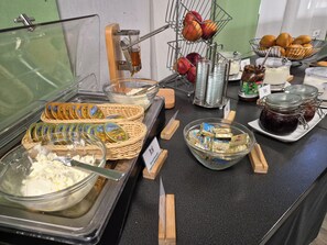 Ein Buffet mit verschiedenen Speisen, darunter Obst, Soßen und Aufstriche.
