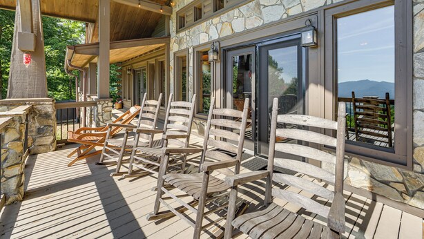 A covered outdoor seating area with wooden chairs and stone walls. - Hot Tub + Fire Pit: Spacious Waynesville Escape! (Waynesville)