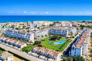 Ein Resort mit mehreren Gebäuden, einem Swimmingpool und Meerblick.