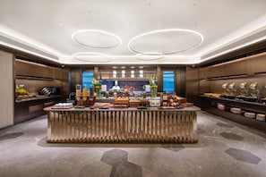 A modern kitchen with a central island, built-in appliances, and a view of the sea. - Crystal Hotel Qingdao Mall of Splendors (Qingdao)