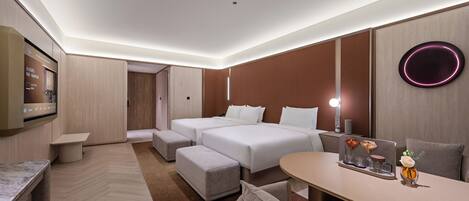 A modern hotel room with a bed, two bedside tables, a desk, and a seating area.