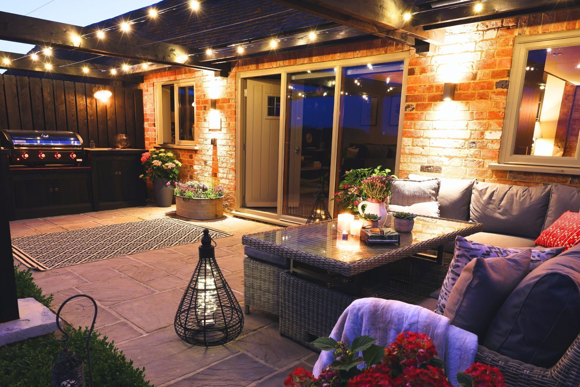 An outdoor patio with a grill, seating area, and potted plants.