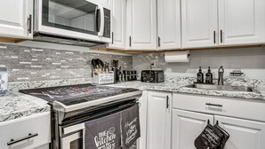 A kitchen with white cabinets, a microwave, a stove, and a sink.