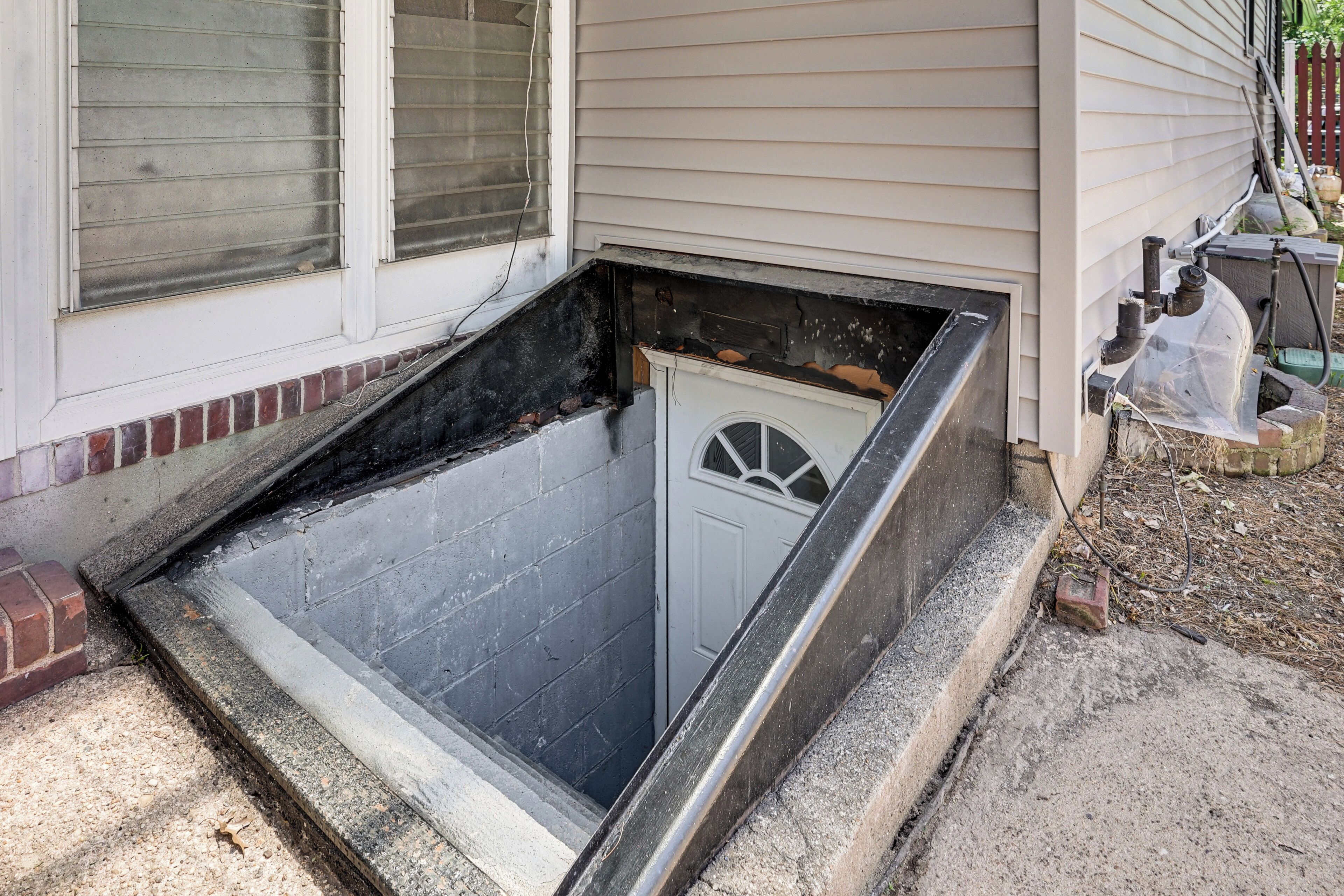 A narrow, enclosed space with a door, a window with blinds, and a small step leading up to it.