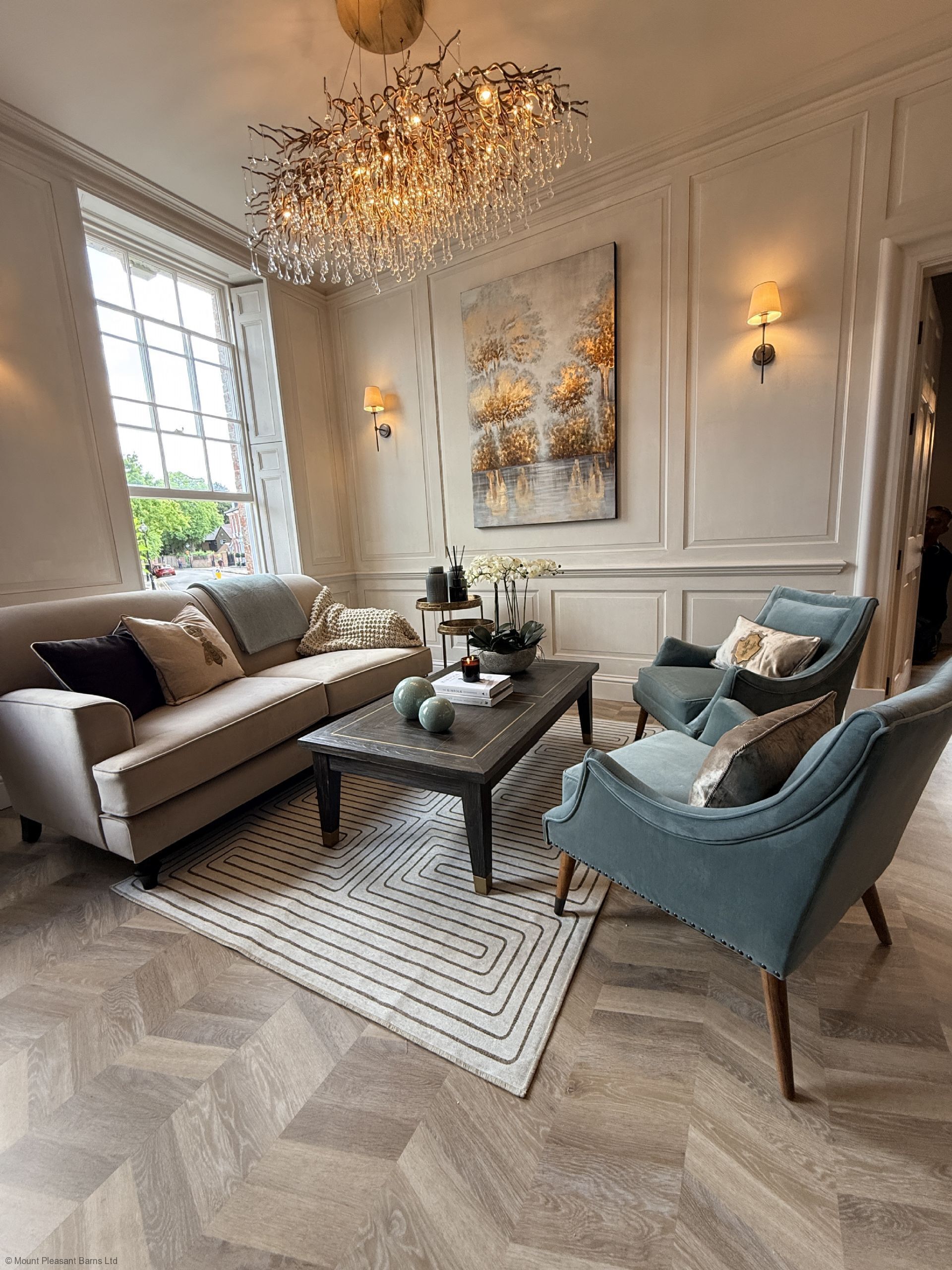 A living room with a sofa, armchair, coffee table, and chandelier.