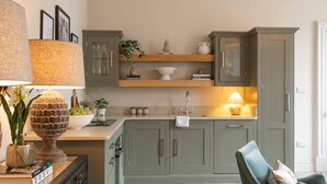 Una cucina con mobili grigi, un piano di lavoro in legno e una sedia.