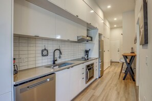 Eine moderne Küche mit weißen Schränken, einem Edelstahl-Geschirrspüler und einem Holzespeisetisch.
