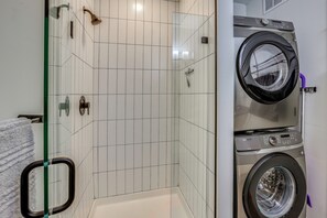 Ein Badezimmer mit Duschkabine aus Glas, einer Waschmaschine und einer Badewanne.