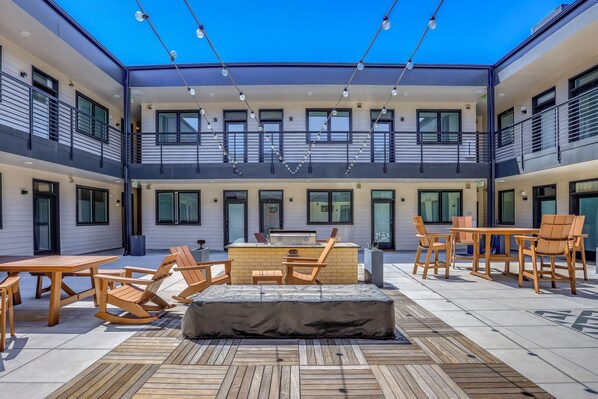 A courtyard with outdoor seating, a barbecue area, and a view of the building's exterior.