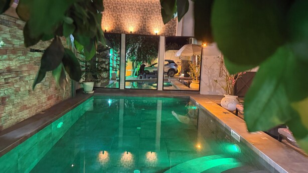 En swimmingpool med ett glasbotten, omgiven av en stenmur och planterade blommor i krukor.