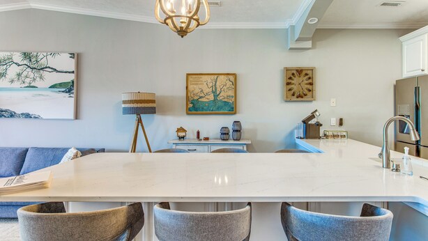 Una cocina moderna con una isla grande, taburetes de bar y un comedor.