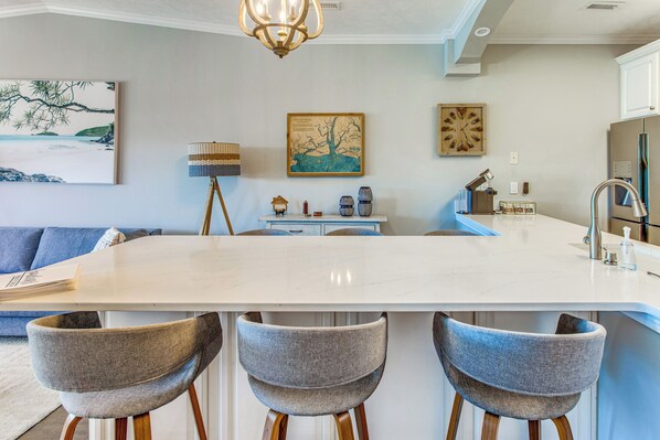Una cocina moderna con una isla grande, taburetes de bar y un comedor.