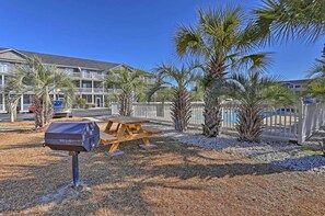 Un edificio con piscina, palmeras y una mesa de picnic.