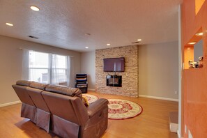 A living room with a leather sofa, a stone wall, a flat-screen TV, and a patterned rug. - Extended Stay w/ Hot Tub! 5 Mi to Old Town ABQ (Albuquerque)