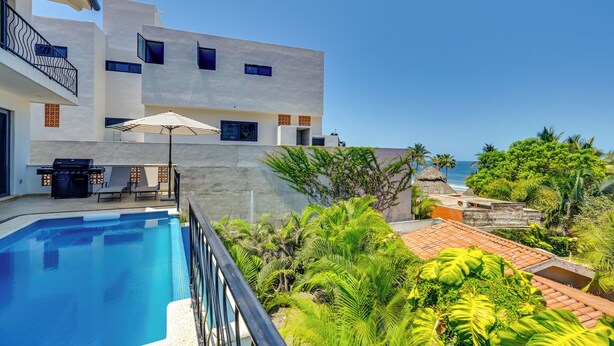 Un bâtiment moderne doté d’une piscine, d’un espace extérieur aménagé et offrant une vue sur l’océan.