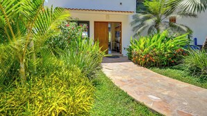 Un chemin menant à un bâtiment doté d’un toit en tuiles et d’une porte.