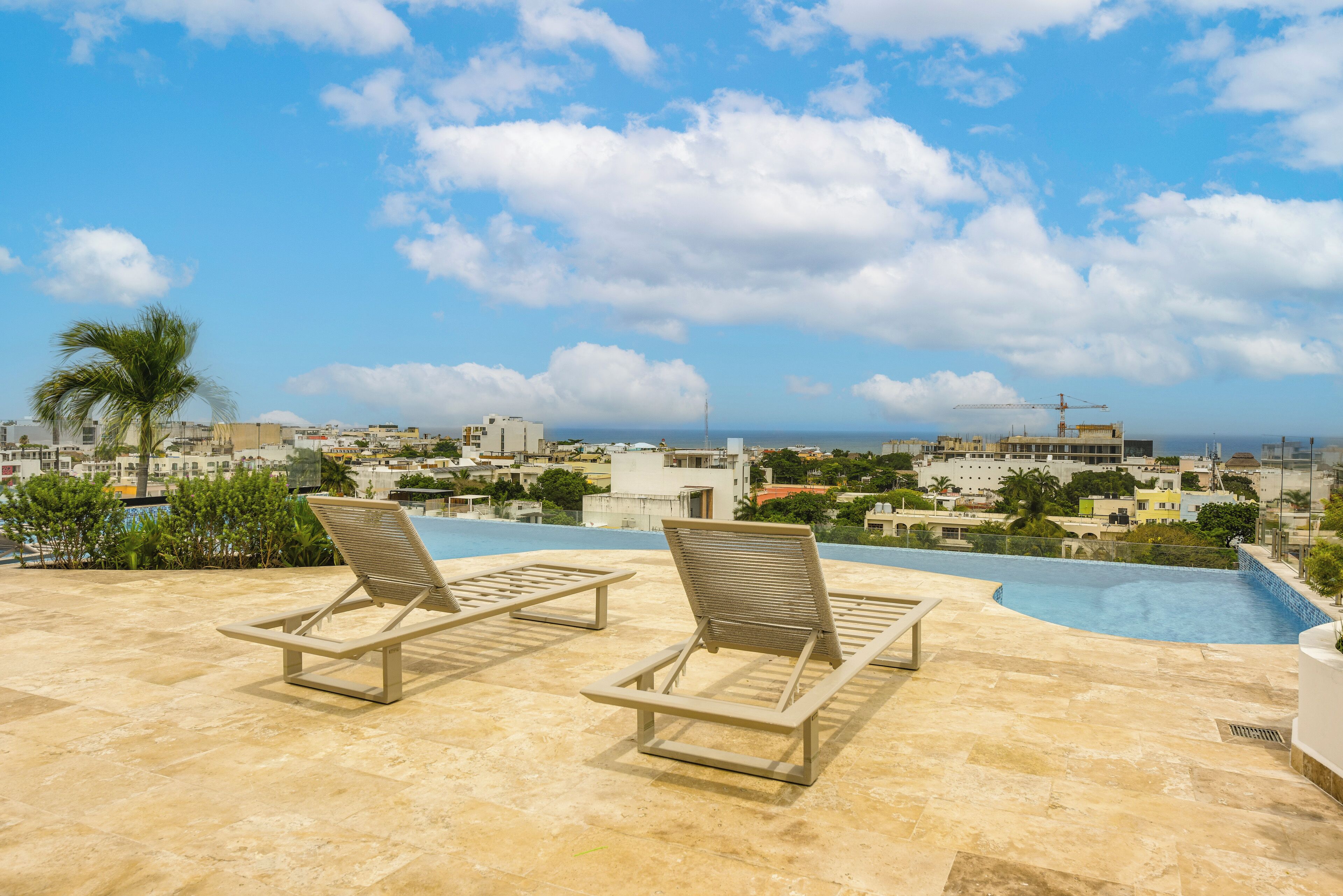 Un espace piscine aménagé sur le toit, avec des chaises longues et une vue sur le paysage urbain.