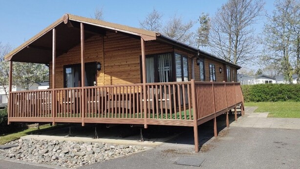 A wooden cabin with a porch, large windows, and a covered deck area.