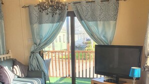 A living room with a sofa, TV, and a flower vase.