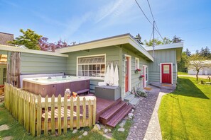 Una casa con jacuzzi, terraza de madera y puerta roja.