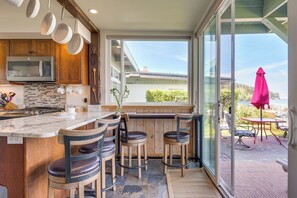 Una cocina con una isla grande, sillas de madera y vistas al exterior.