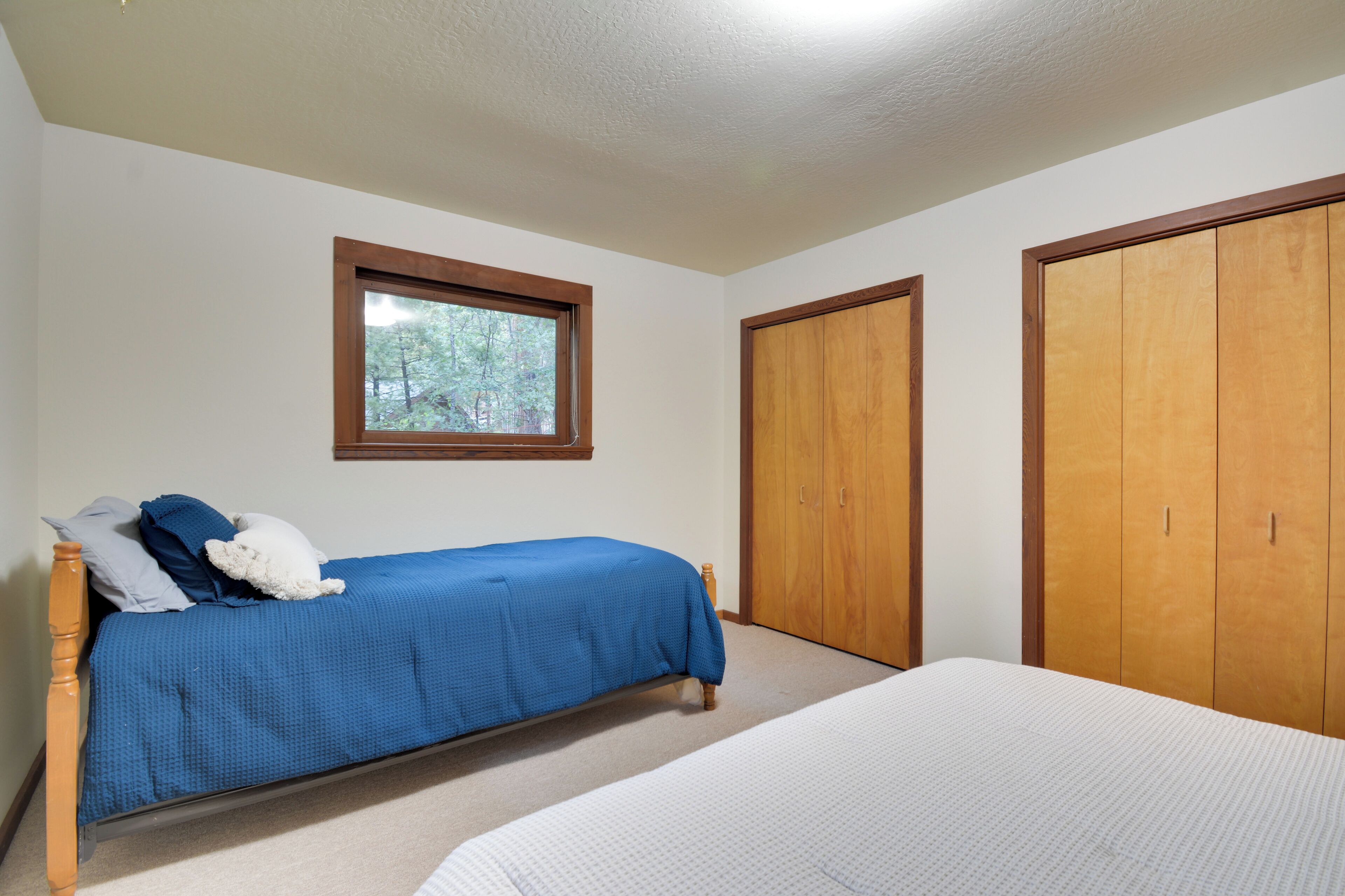 Une chambre avec un lit simple, une fenêtre et deux armoires.