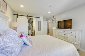 A bedroom with a bed, dresser, television, and a door leading to a bathroom. - Pool Access! Family Getaway in Hilton Head Resort (Hilton Head Island)