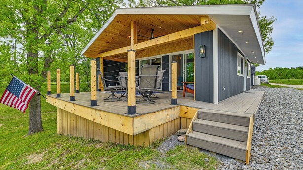 Una casa moderna con terraza de madera, mobiliario exterior y una bandera.