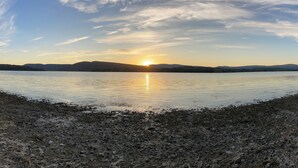 Un lago tranquilo al atardecer, con cielo despejado y montañas lejanas.