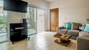 Un soggiorno moderno con una TV a schermo piatto, un divano, un tavolino da caffè e una porta scorrevole in vetro che dà su un balcone.