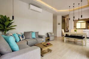 A modern living room with a sofa, coffee table, and dining area. - Modern Condo: Steps to Mamitas Beach Club/5thAve (Playa del Carmen)
