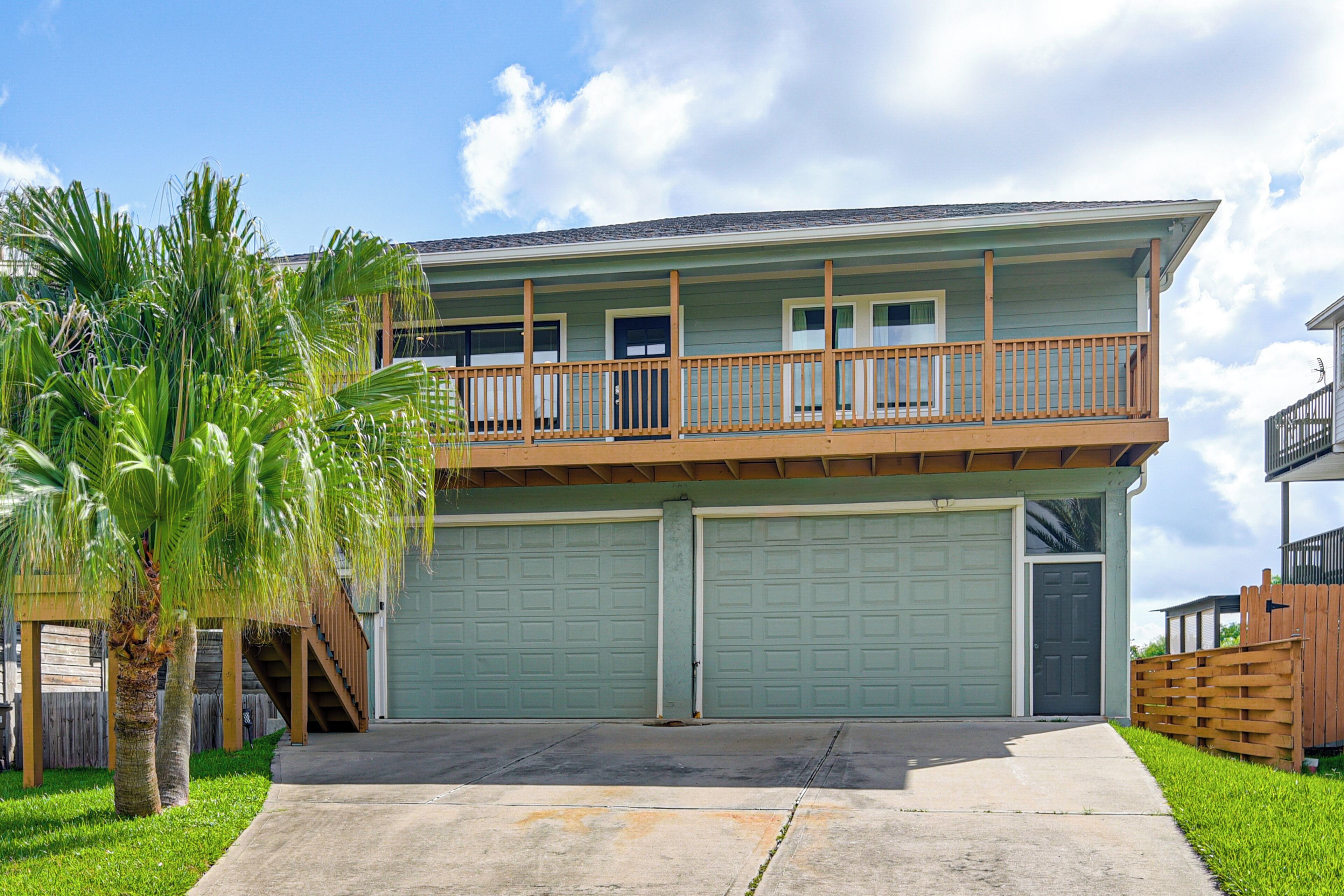 A two-story house with a balcony, a garage, and a palm tree.