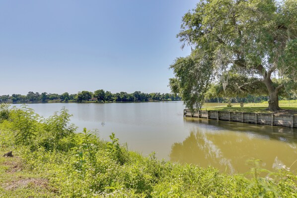 Un lago tranquilo con un muelle, rodeado de vegetación y árboles.