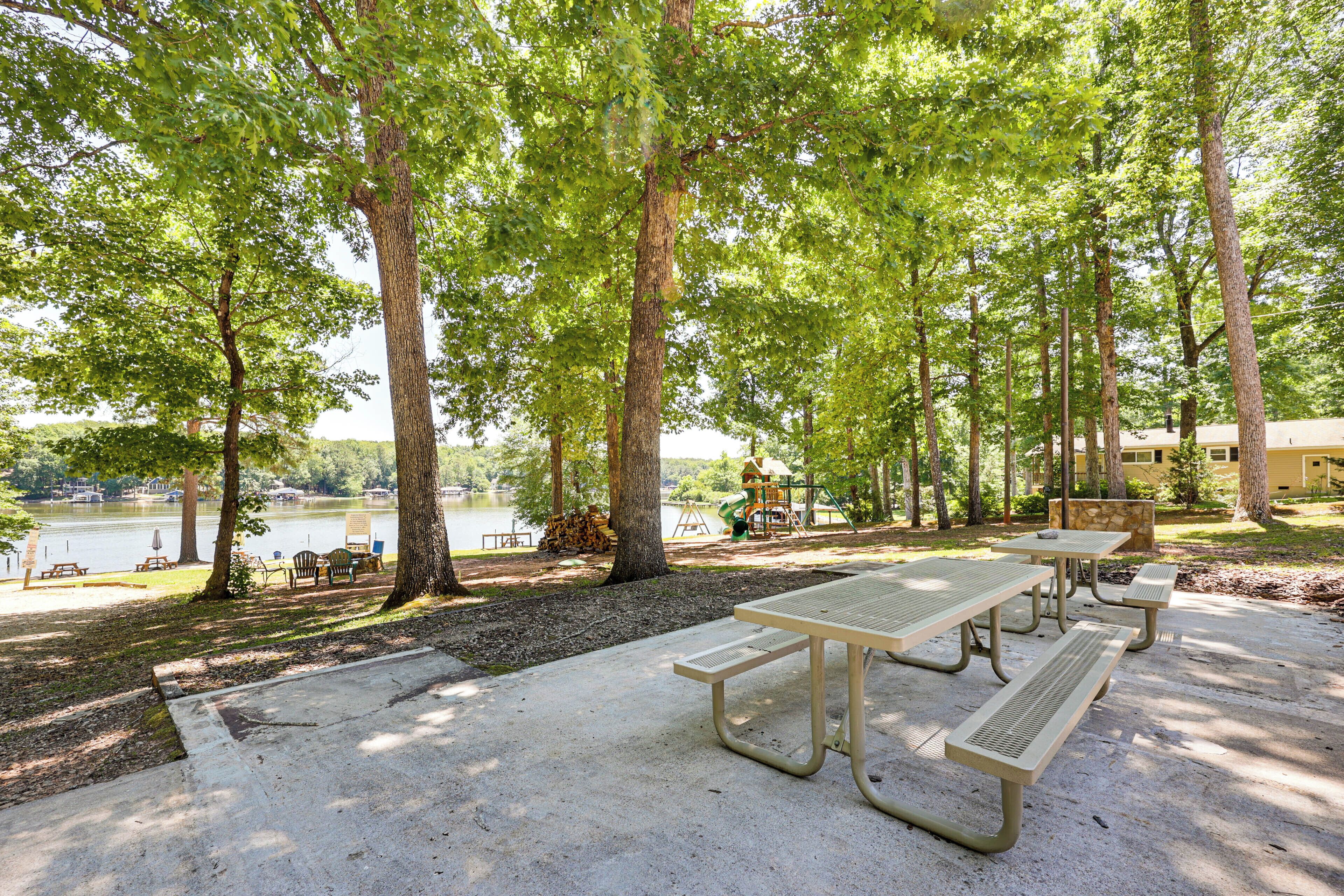 Ein Park mit Picknicktischen, einem Spielplatz und Blick auf einen See.
