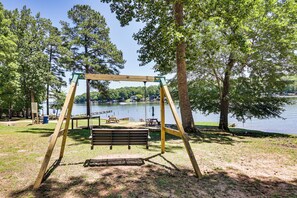 Un ensemble de balançoires en bois installé près d’un lac, avec des tables et des bancs pour pique-niquer.