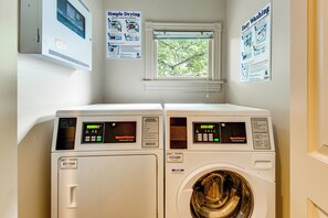 A laundry room with two front-loading washers and dryers, a window with a view of trees, and instructional posters on the wall. - ATL Commuter's Dream! 1/2 Mi to MARTA in Decatur (Decatur)