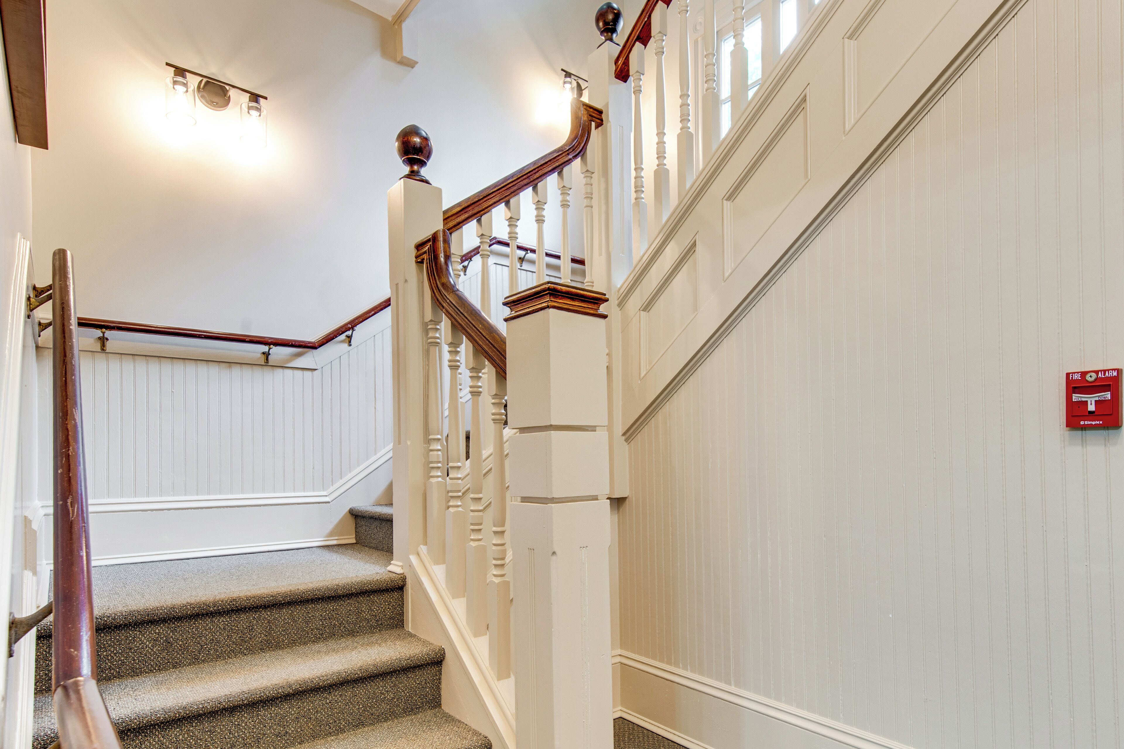 A staircase with a wooden handrail and white walls.