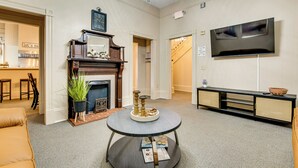 Een woonkamer met een open haard, een ronde salontafel, een televisie en een bank.
